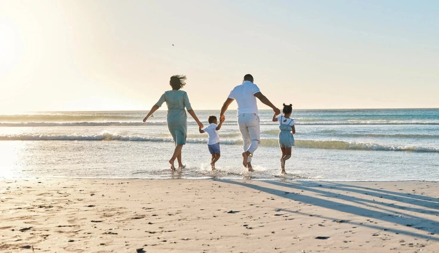 A family walking along the shoreline at sunset