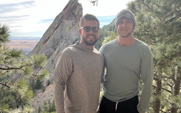 Sean, in sunglasses, hiking with his brother below the Flatirons in Boulder, Colorado