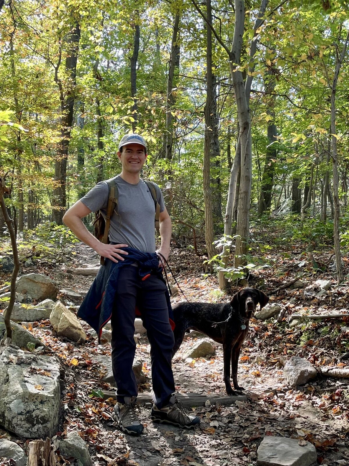 Zealan hiking a wooded trail with his dog